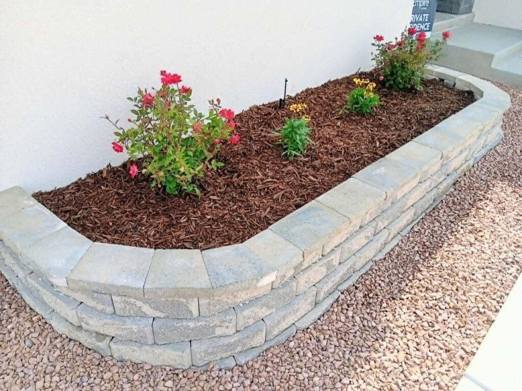 Tiered natural stone retaining wall creating level patio space

